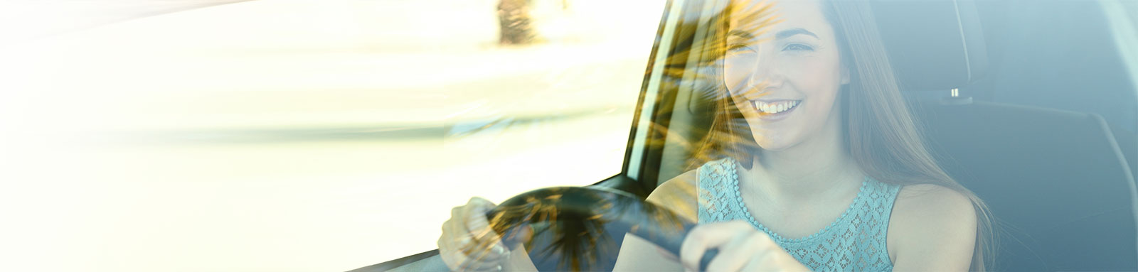 A young woman drives a car with a smile