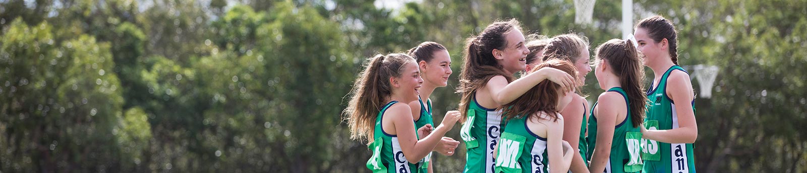 Group of netball girls celebrating on outdoor court