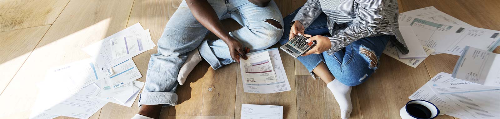 Couple on the floor looking at papers and bills with a calculator