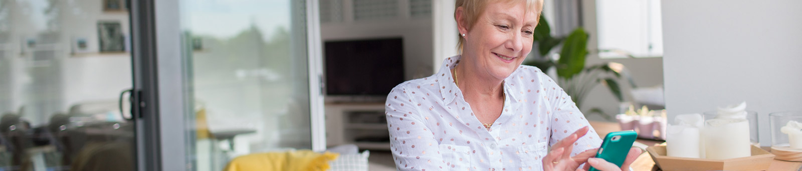 Lady in white shirt using smartphone while sitting at kitchen