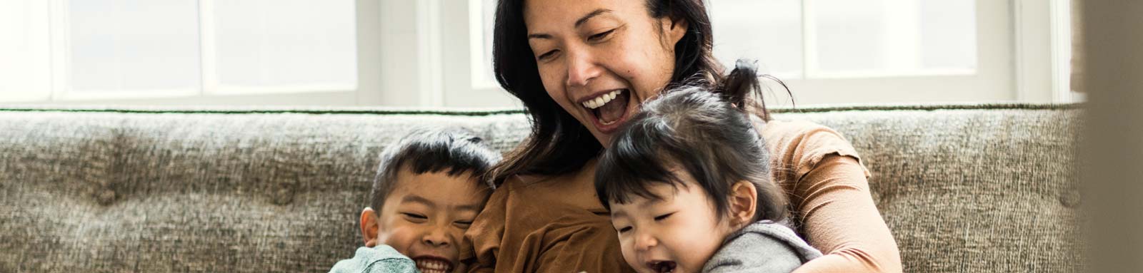 Mother and kids smiling on a couch at home