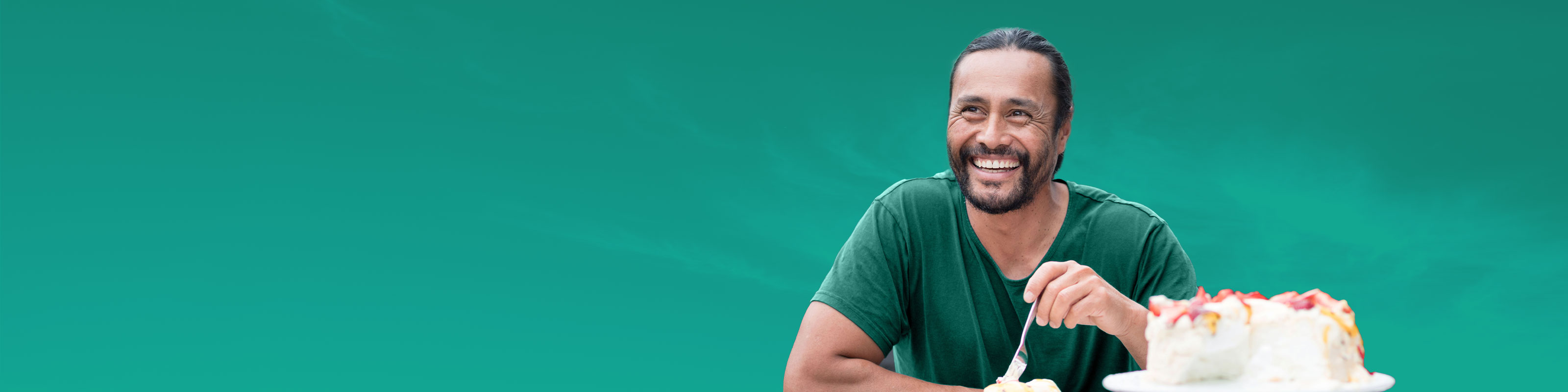 man with a fork eating cake with a green background