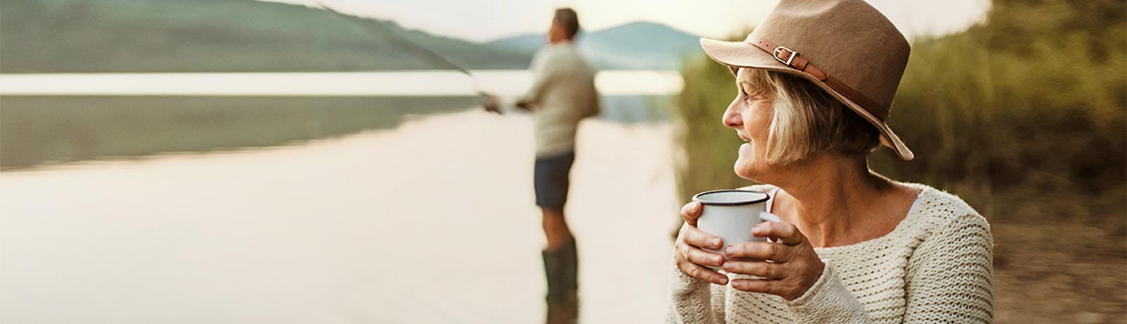 Woman holding a cup and a man fishing