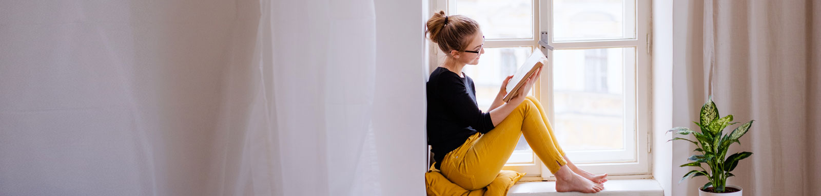 Woman reading a book on a windowsil