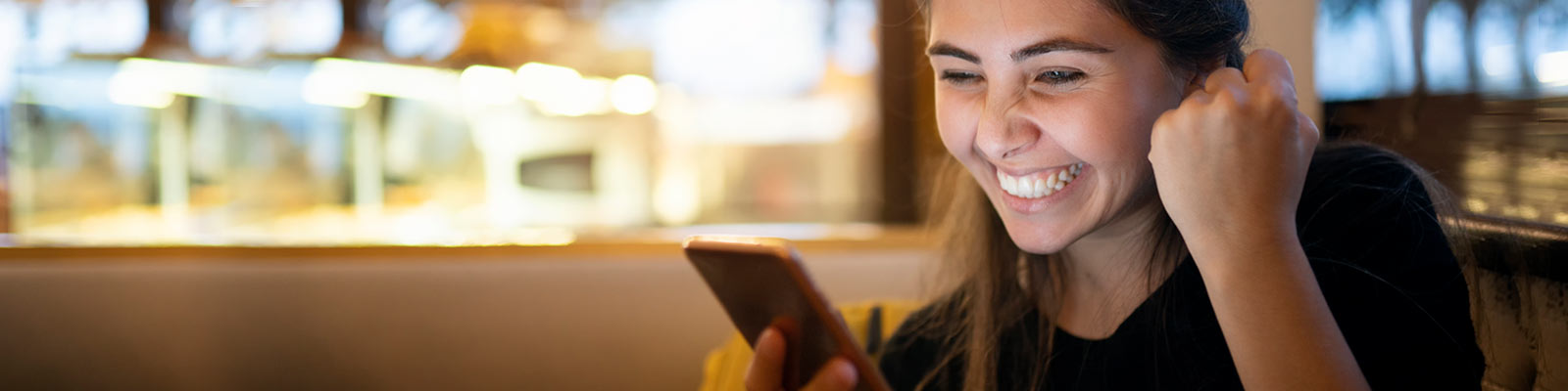 Woman looking at phone, smiling and pumping fist