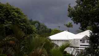 House surrounded by trees with grey clouds overhead