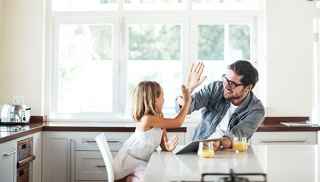 Father and daughter high five in kitchen