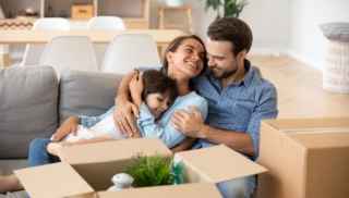 Family sitting on couch with moving boxes around