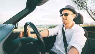 Man driving convertible car in countryside