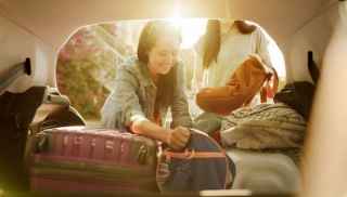 Two women stacking bags into car boot