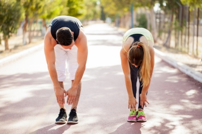 woman and man stretching - back curls in the park