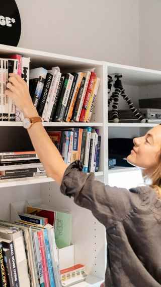 Woman reaching for book on bookshelf